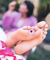 Ansicht zweier Füße, Blüte klemmt zwischen zwei Zehen