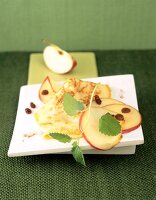 Apple pancakes garnished with fresh apple slices and raisins on board