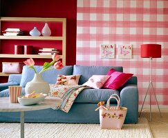 Cosy living room with light blue sofa, cushions, pink plaid wallpaper and shelf