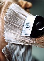 Extreme close-up of woman with blonde hair applying smoothing cream with a brush