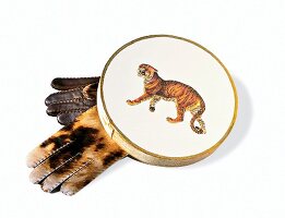 Handschuhe aus Kalbsfell arrangiert unter Spanschachtel mit Tiermotiv
