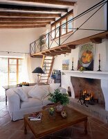 Living room with beamed ceiling, stairs, white sofa and fireplace