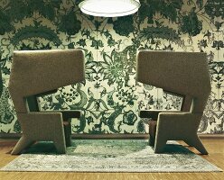 Oversized wing chairs in front of floral patterned wallpaper