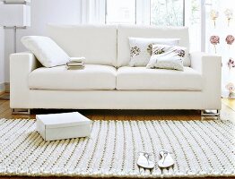 Weißes Sofa auf Holzfußboden, davor Teppich, "vorher"