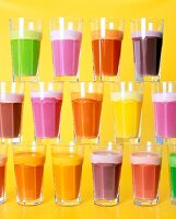Stack of glasses with multicolour diet drink in against yellow background