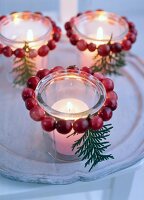 Tea light candles in glass decorated with Christmas decorations on table