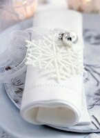 Close-up of white napkin with snow flake and ribbons on plate