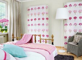 Iron bed with pink blanket, lamp and chair in bedroom