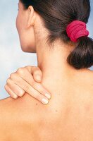 Rear view of woman performing acupressure for shoulder and neck pain