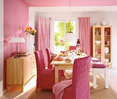 Essplatz in Rosa: helle Holzmöbel, pinkfarb. Überzüge, Wand rosa + weiß