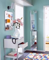 Telephone and flower vase on table with mirror, lamp and colourful tiled floor in hallway