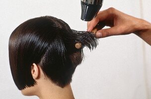 Close-up of woman with mushroom head getting hair blow dried by hairdresser