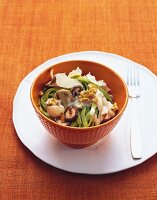 Bowl of green ribbon pasta with walnut sauce on plate with fork