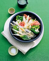 Asparagus salad with spinach and prosciutto in bowl
