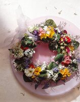 Wreath of spring flowers and rose plate on round table