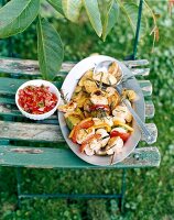 Baked potatoes and gefluegelspiessen on plate with spoon on wooden bench