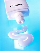 Close-up of white cleanser by Chanel and tube squeezed out on blue background