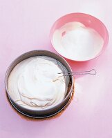 weiße Tortencreme in Springform + rosa Schüssel mit weißer Creme