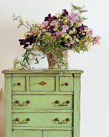 Bouquet of flowers on green chest of drawers