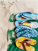 Sommerschuhe, Flipflops in einer Reihe im Sand am Strand, Detail