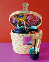 Tea set in a rattan basket against pink and red background