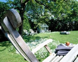 Close-up of wooden deck chair in garden during summer