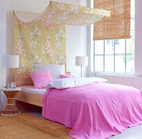 Bedroom with pink bed sheet and floral patterned canopy