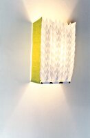 Illuminated paper lamp hanging on white wall