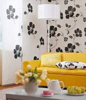 Living room with yellow sofa in front of white floral pattern curtain