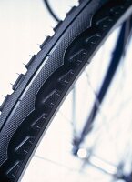 Close-up of bicycle tire with grips and steel spokes