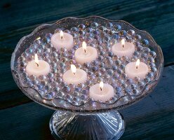 Close-up of tea light candles with glass marbles on glass cake stand