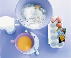 Rührschüssel mit Mehl, Ei und Milch, daneben drei Eier und Butter. Nr.1