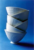 Stack of porcelain tea cups with different pattern on blue background
