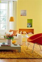 Living room in yellow with white sofa, orange armchair, table and floor lamp