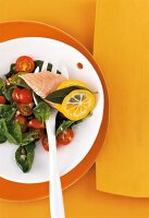 Spinach salad with tomato and salmon fillet on plate