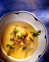 Cream of potato soup with oyster mushrooms in bowl, overhead view