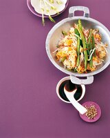 Fried rice with stir fried vegetables in wok on purple background, copy space