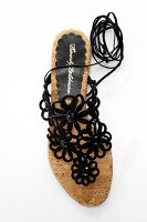 Sandalen geschmückt mit schwarzen Stoffblumen und Wickelbändern