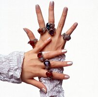 Close-up of woman's hands wearing colourful and dazzling rings made in chased silver