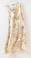 Floral pattern beige silk summer dress hanging on coat hanger