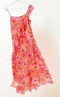 Orange and red summer dress in hanger on white background