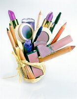 Various beauty products tied together with a ribbon on white background