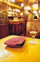 Damentasche und Glas auf einem Tisch in einer Bar, Hintergrund unscharf
