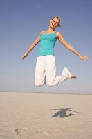Frau am Strand springt freudig in Luft