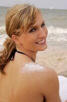Portrait of cheerful blonde woman with salt crystals on shoulder wearing bikini, smiling