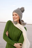 Beautiful woman wearing green sweater, jeans and scarf standing with arms crossed, smiling