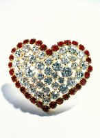 Close-up of red and white heart shaped brooch on white background