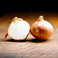 Whole and halved onion on wooden table