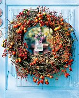 Spiral wreath of rose hips and hops on blue door