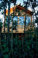 Baumhaus aus Holz auf 2 Meter hohen Stelzen umgeben von Erlen